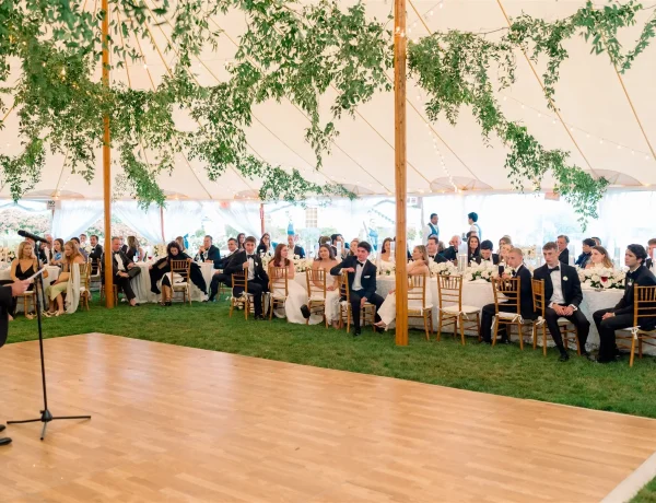 Daytime interior Sperry sailcloth tent with center pole and greenery decor. and dance floor.