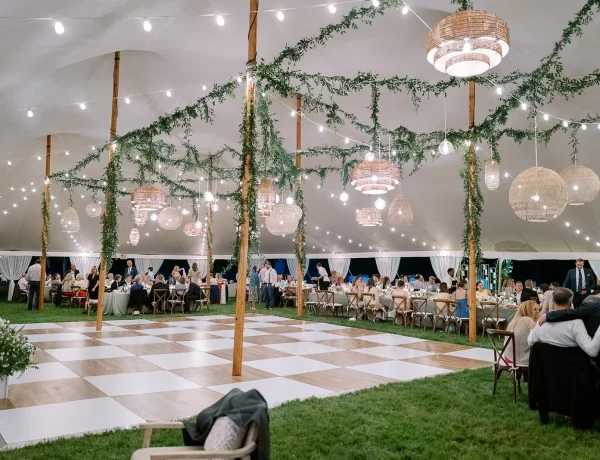 Daytime interior Sperry sailcloth tent with center pole and greenery decor. and dance floor.